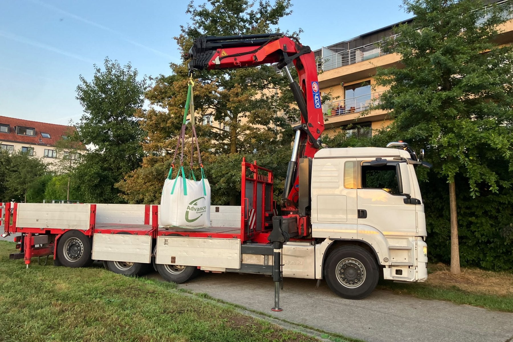 Vrachtwagen met kraan van Advance Greenshop lost een big bag